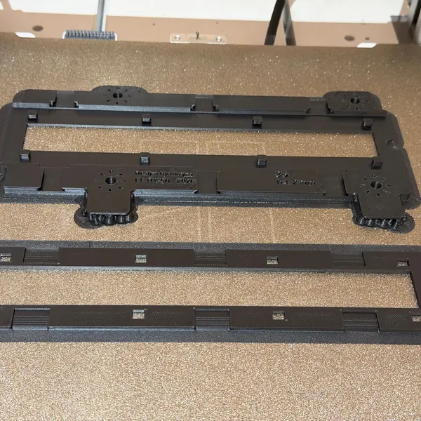 Portanegatius de 35 mm imprès en 3D en negre, en dues peces, sobre la placa d'impressió